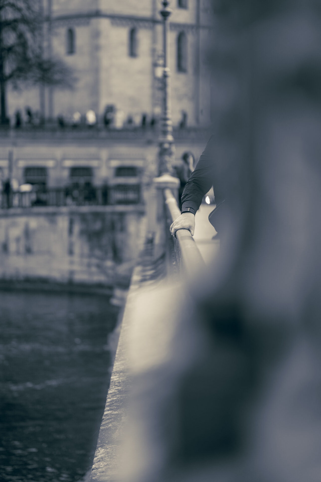 In the heart of urban stillness, a human element emerges. A sleeve, a hand casually draped, brings the scene alive. It hints at stories unfolding just beyond our view. The backdrop's blur makes this touch the anchor in a sea of soft focus, a subtle nod to the human thread in the city's fabric.
