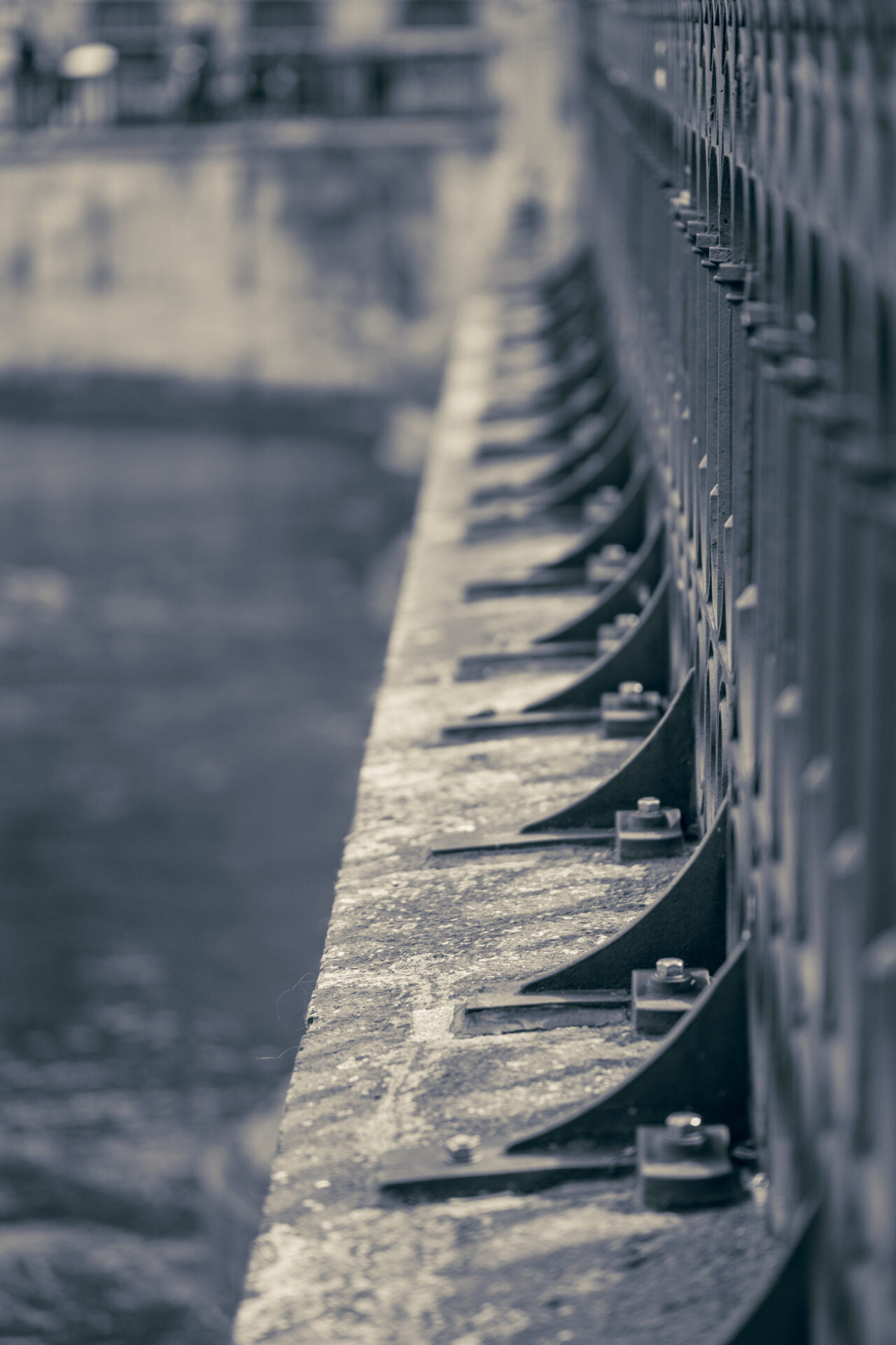 A bridge railing leads the eye, its pattern a testament to sturdy craftsmanship. The sepia tone whispers of time, perhaps reflecting moments shared or solitary thoughts of passersby. Each bolt and curve tells of structure and story, much like notes on a staff, composing a silent symphony.