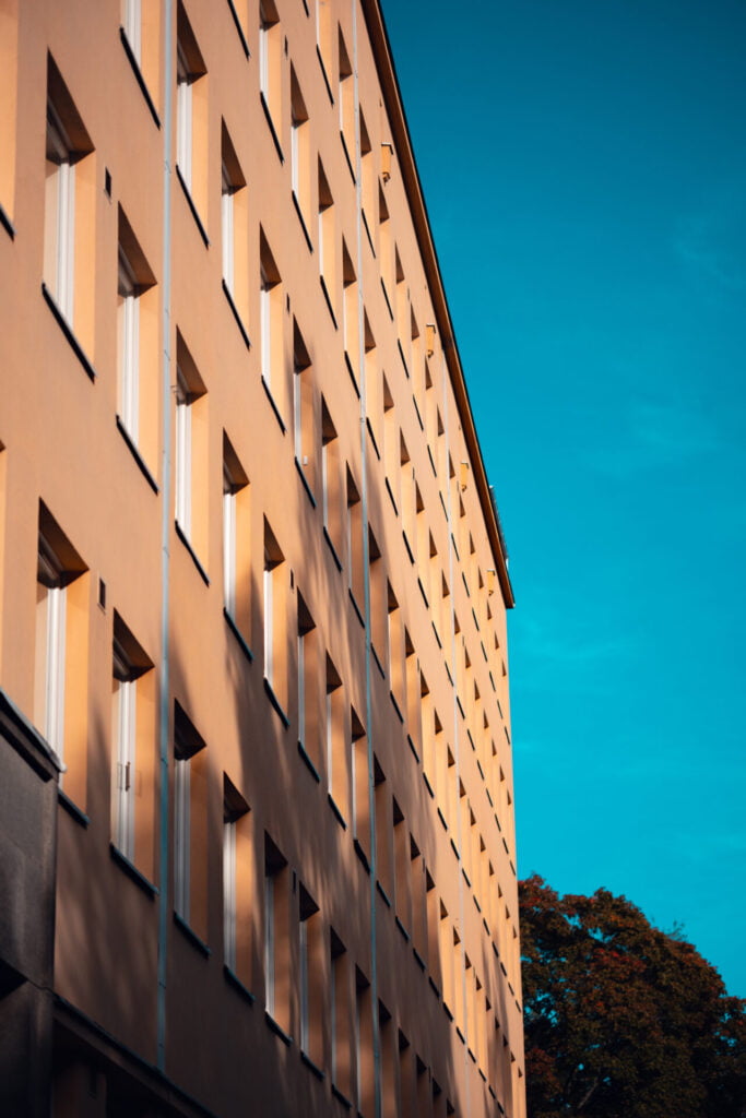 2023 09 14 - 154913 - Milan Ivanovic Photography Modern building facade bathed in warm sunset light with clear blue sky.